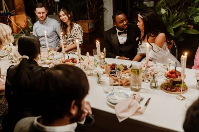 Des convives partagent un dîner chaleureux autour d'une table illuminée de bougies lors d'un mariage intime.